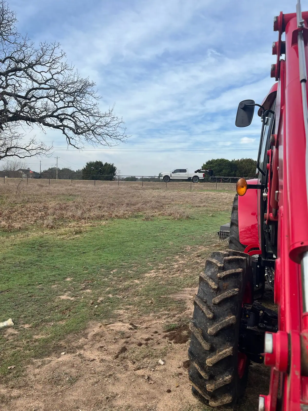 Brush hog mowing a pasture under mature oaks with a red tractor near Granbury, TX