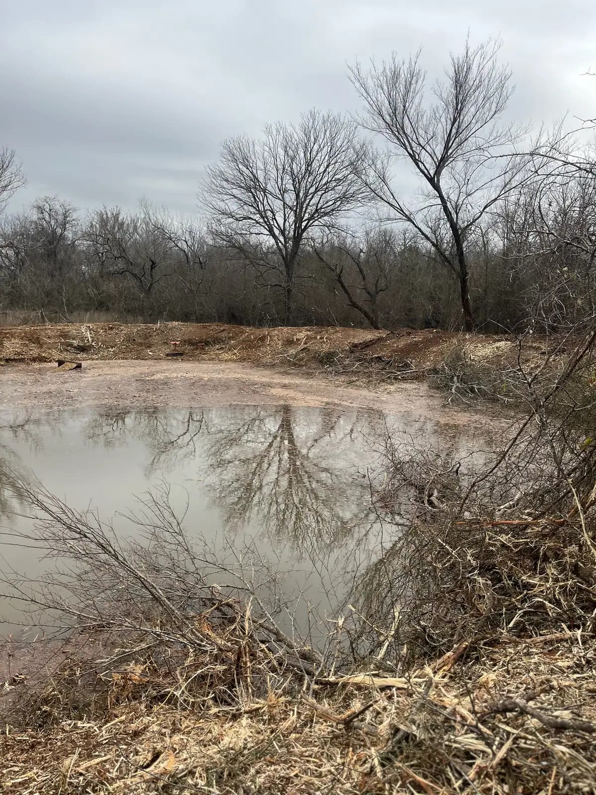 Stock pond banks cleared of brush and reshaped on a ranch near Granbury, TX
