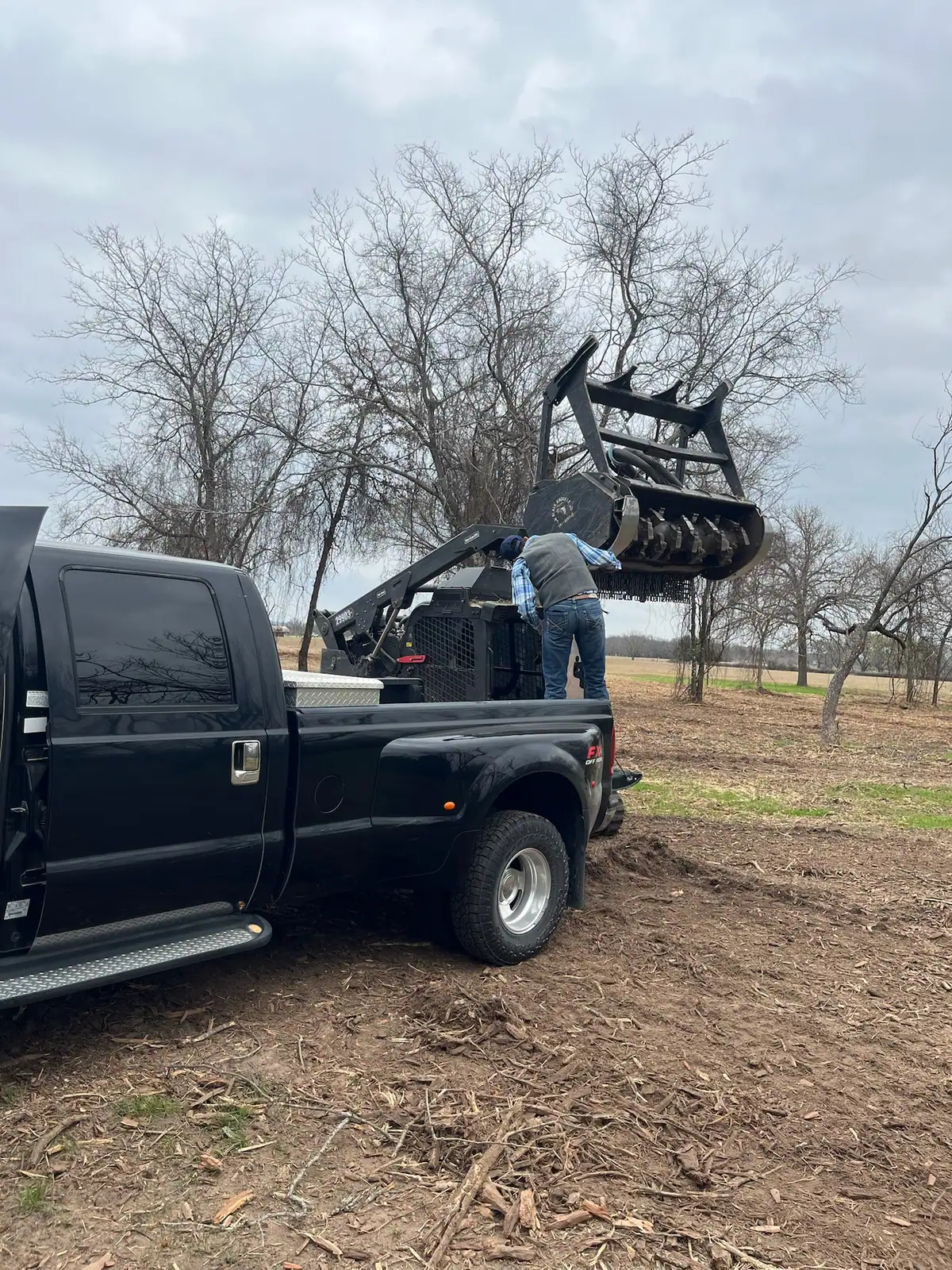 Black Knuckle Land Management truck and trailer hauling the skid steer to a land clearing job near Granbury, TX